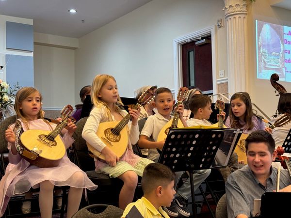 Young children playing mandolins and guitars in the church orchestra