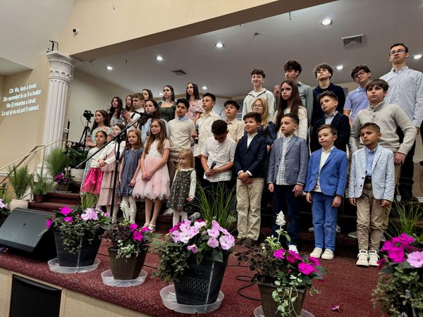 Children and youth choir singing on the church stage, surrounded by spring flowers