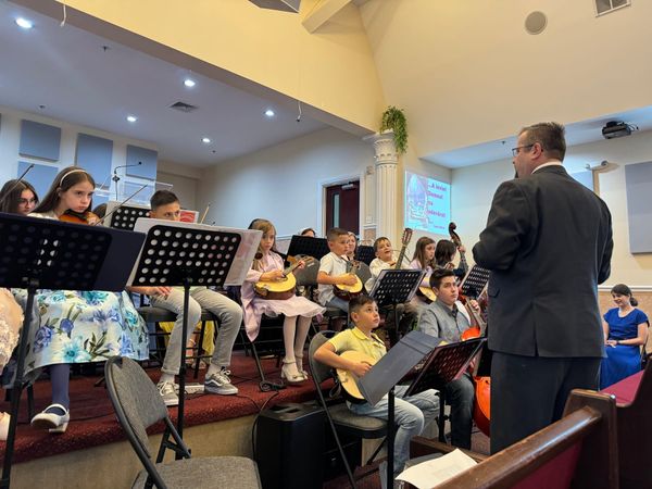 The children's orchestra performing on stage with their conductor