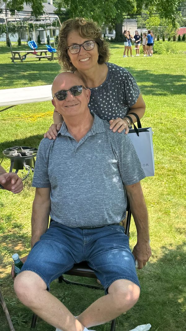 A smiling couple sitting outdoors in the sun